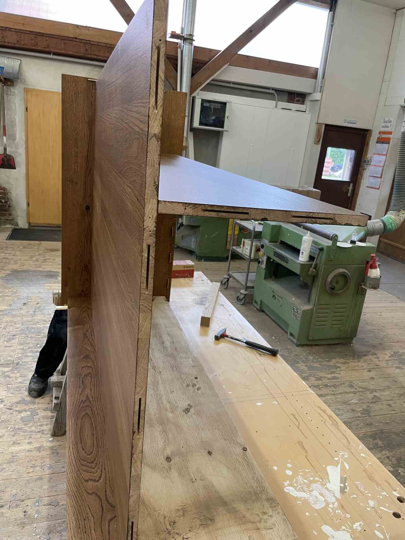 Eine Person bearbeitet in einer Werkstatt ein Stück Holz.