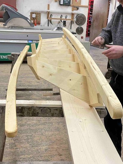Ein Mann arbeitet in einer Werkstatt an einem Holzboot