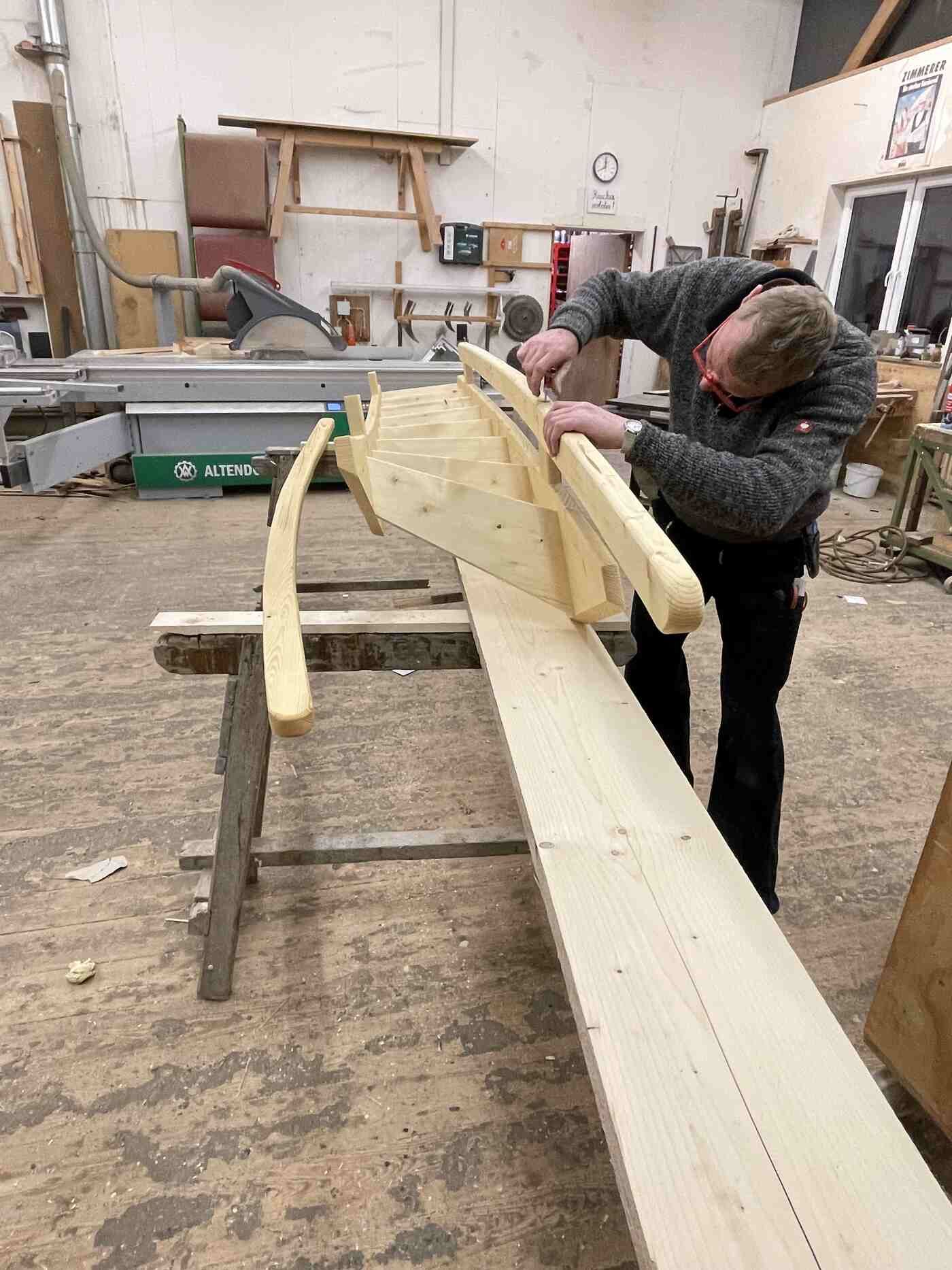 Ein Mann bearbeitet in einer Werkstatt ein Stück Holz.