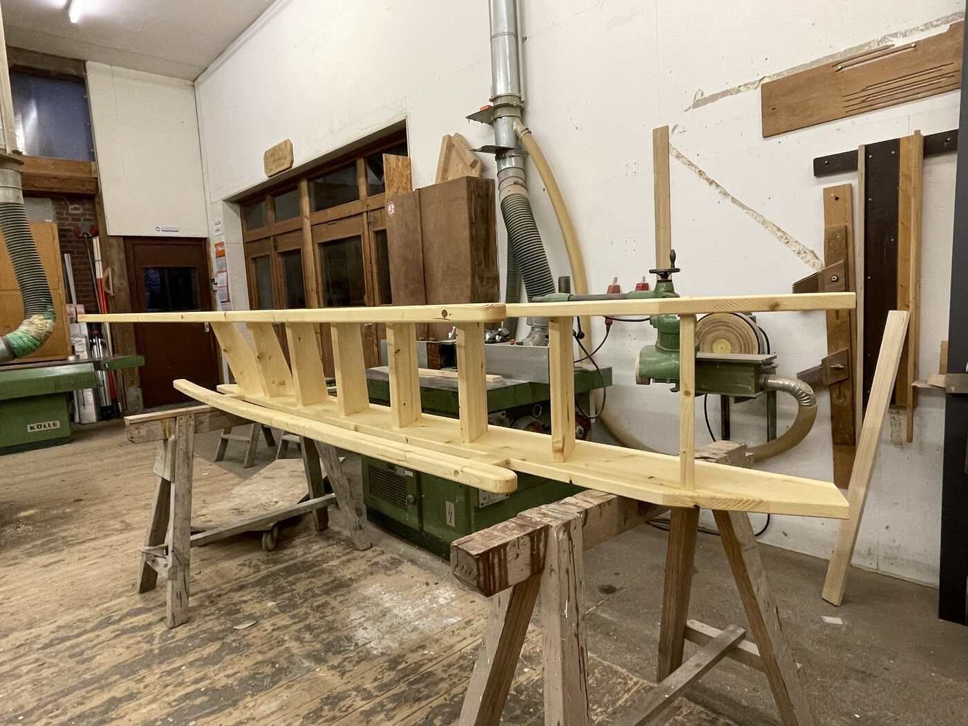 In einer Werkstatt steht eine Holzleiter auf einem Holzbock.