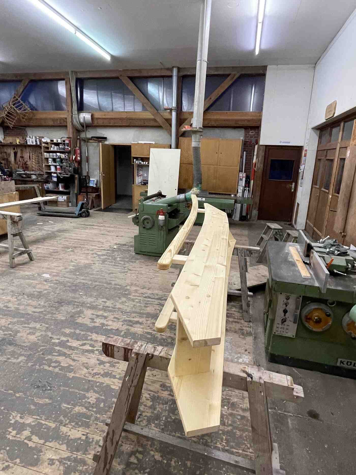 In einer Holzwerkstatt liegt ein großes Stück Holz auf einem Holzbock.