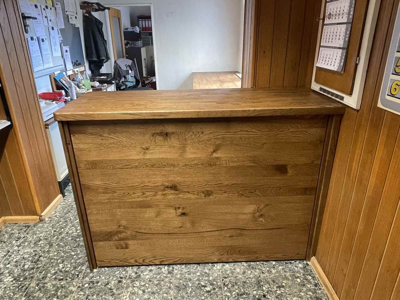 Eine Holztheke in einem Raum mit einem Kalender an der Wand.