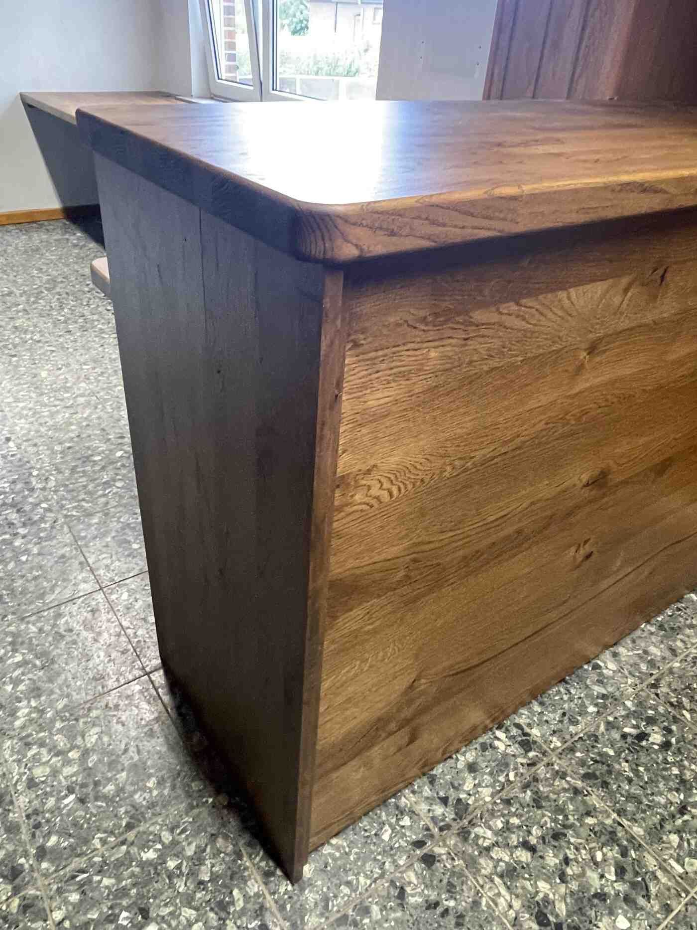 In einem Raum steht ein Holztisch auf einem gefliesten Boden.