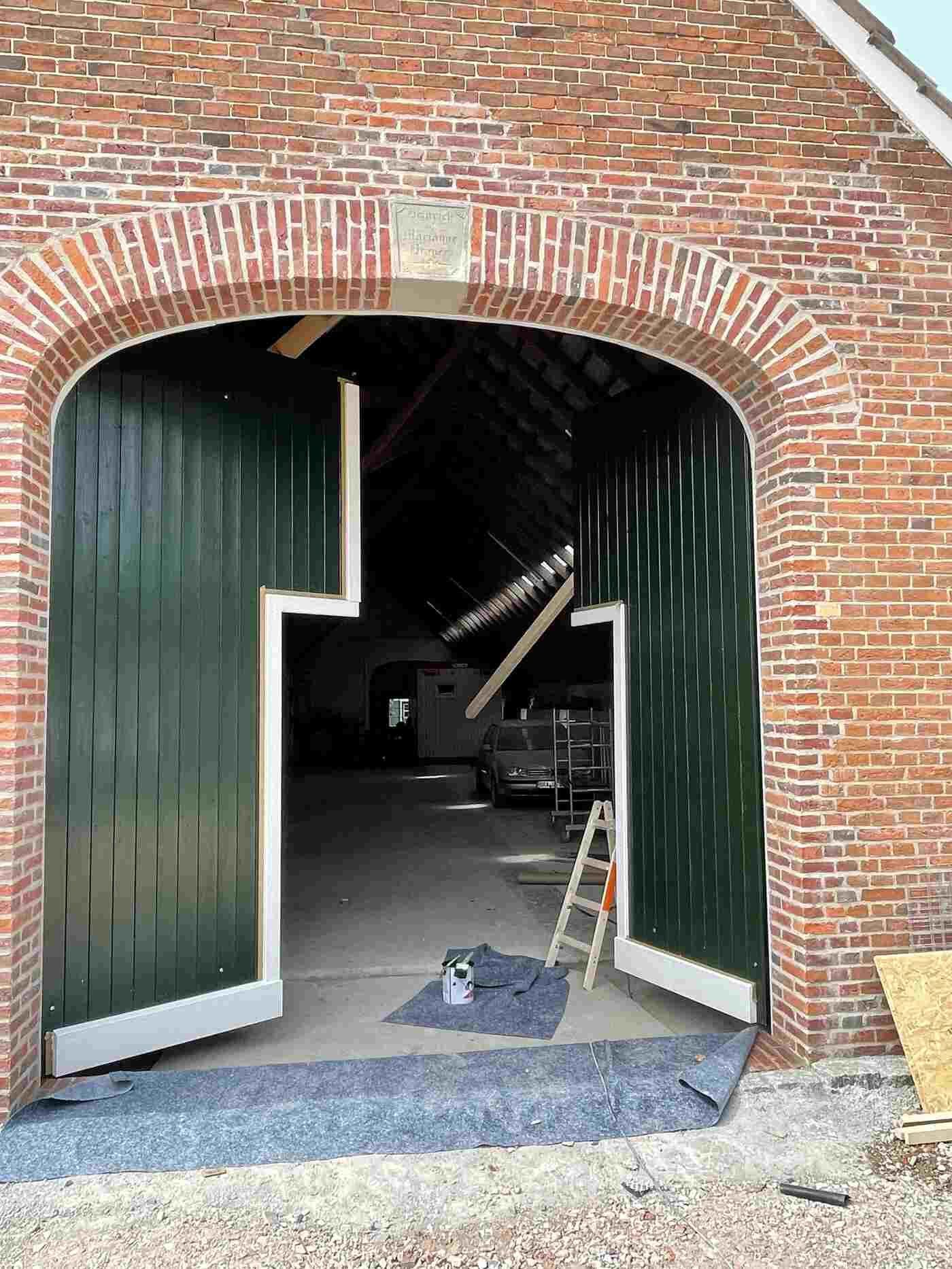 Ein Backsteingebäude mit grünen Türen und einer Leiter davor.