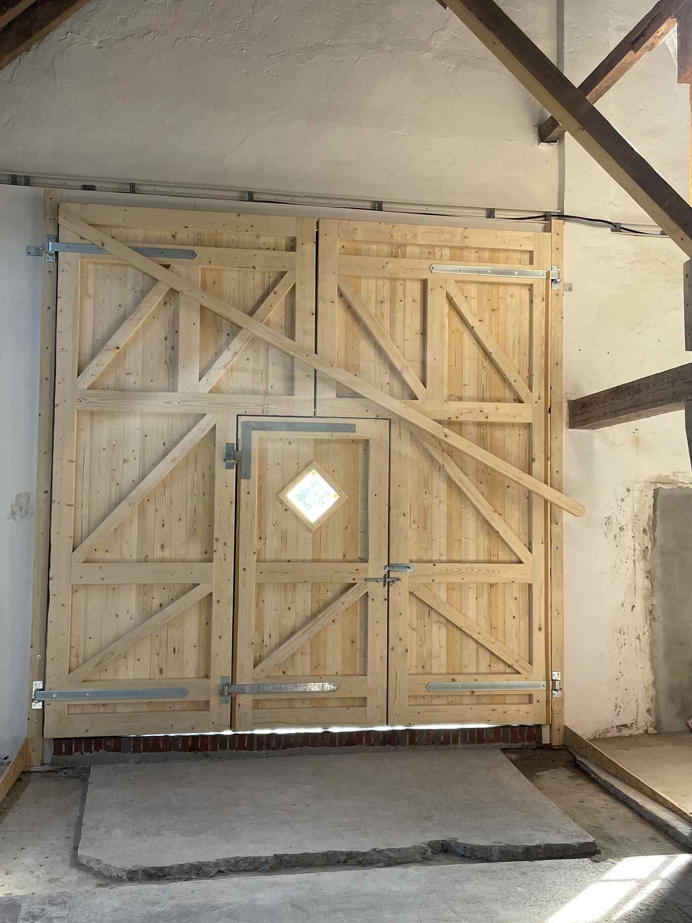 Ein hölzernes Garagentor mit einem Fenster in der Mitte.