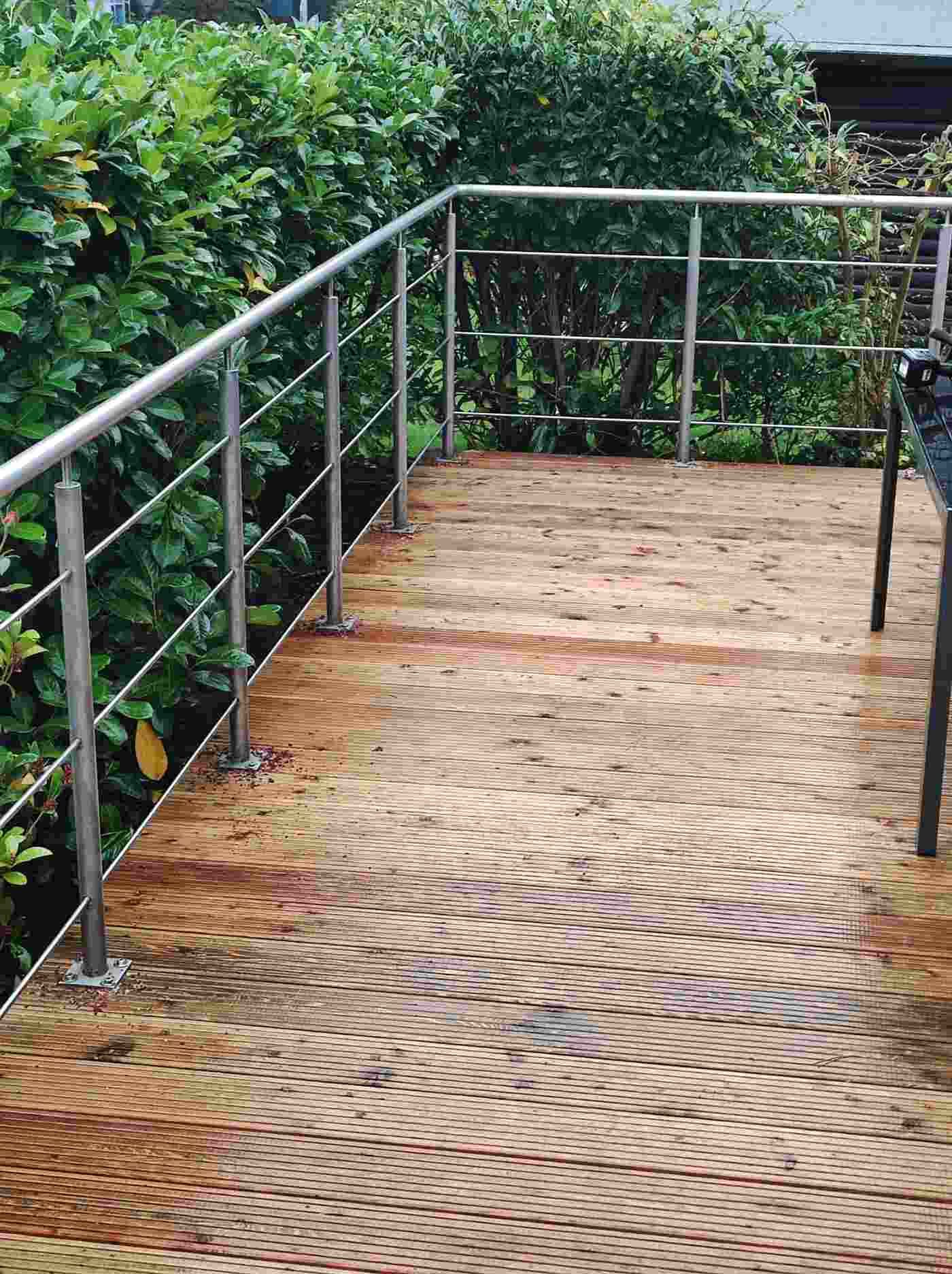 Ein Holzdeck mit einem Metallgeländer und einem Stuhl darauf.