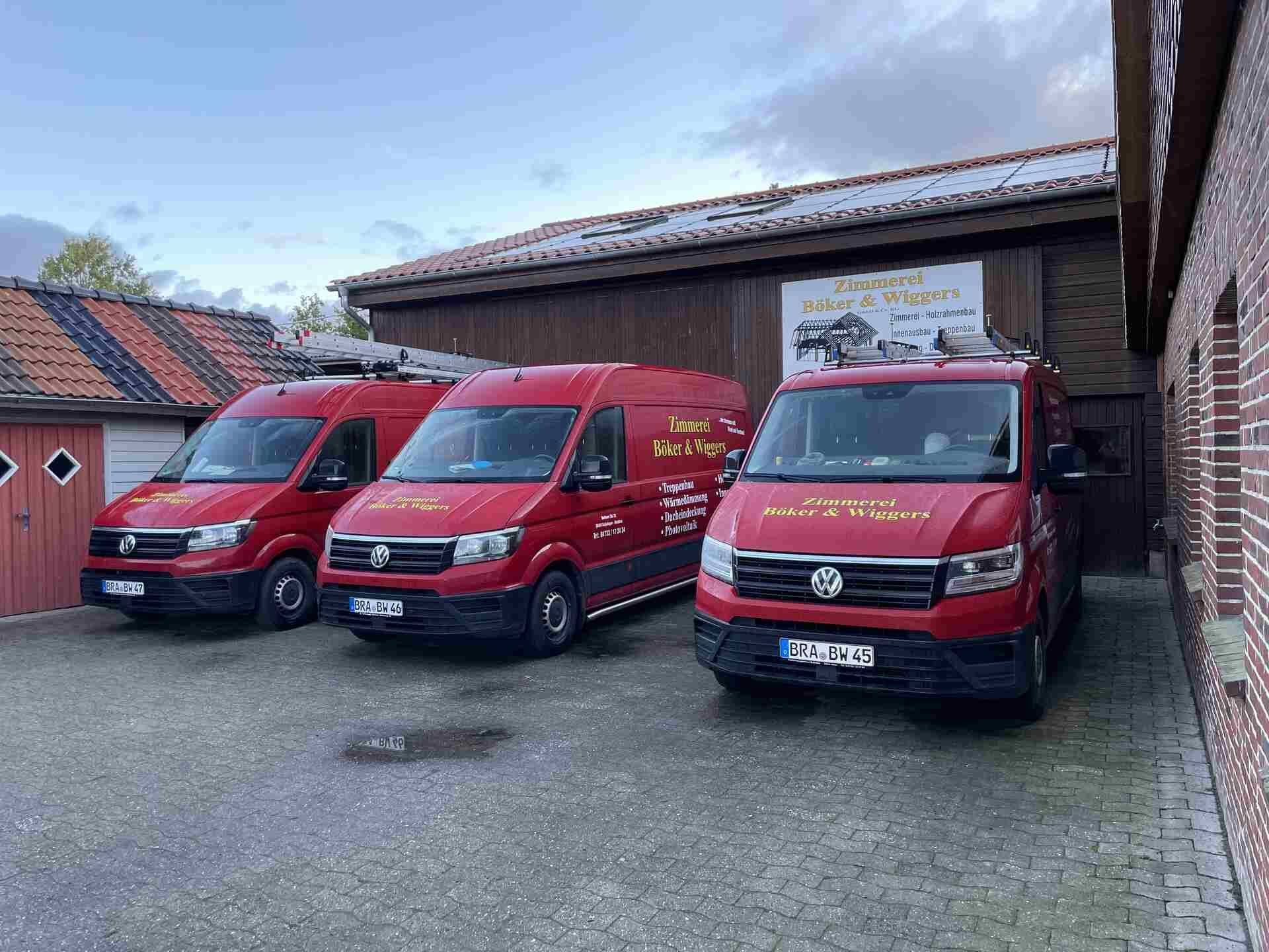 Drei rote Lieferwagen parken vor einem Backsteingebäude.