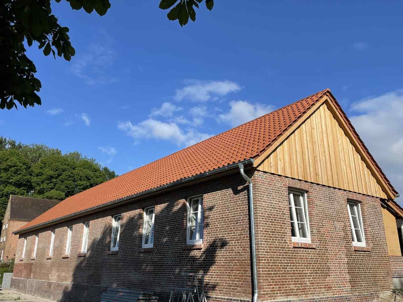 Ein Backsteingebäude mit einem roten Dach und einem Holzdach