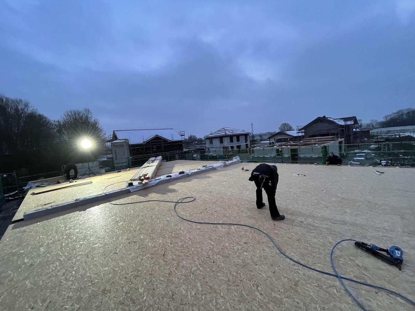 Ein Mann arbeitet nachts auf einem Holzdach.