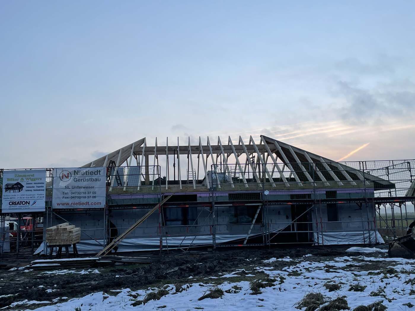 Auf einem schneebedeckten Feld wird ein Haus gebaut.