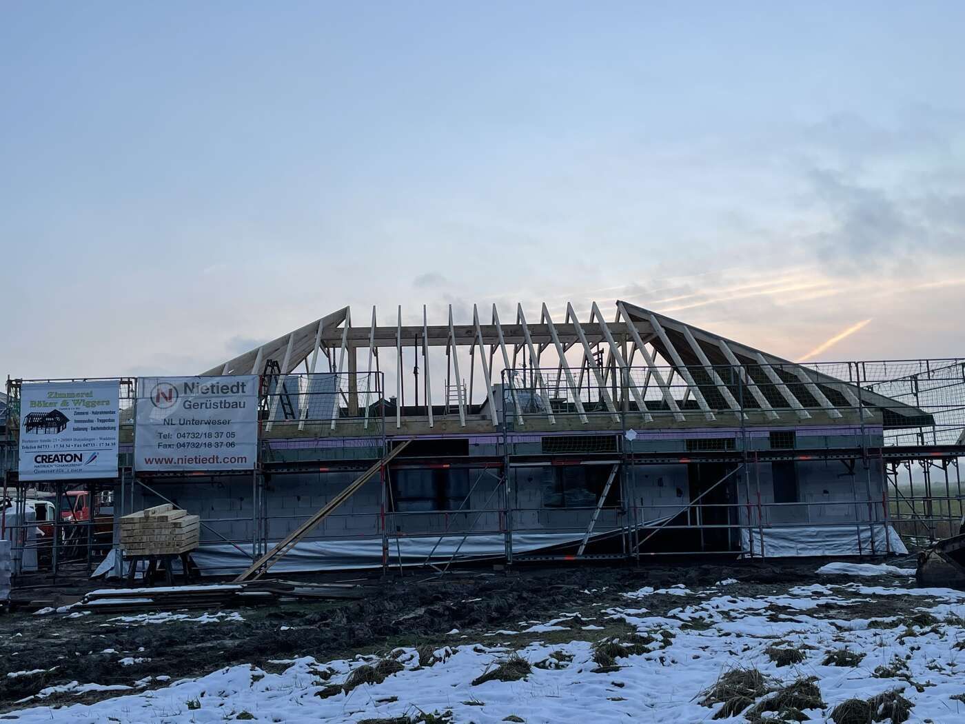 Auf einem schneebedeckten Feld wird ein Haus gebaut.