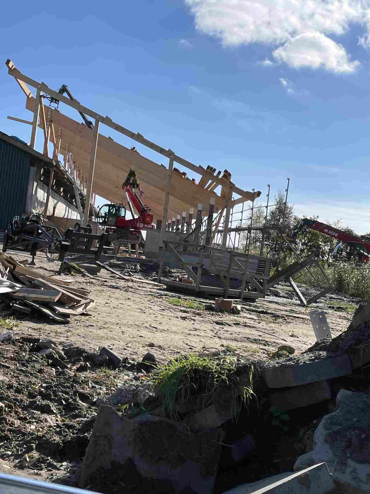 Auf einem Feld wird eine große Holzkonstruktion errichtet.