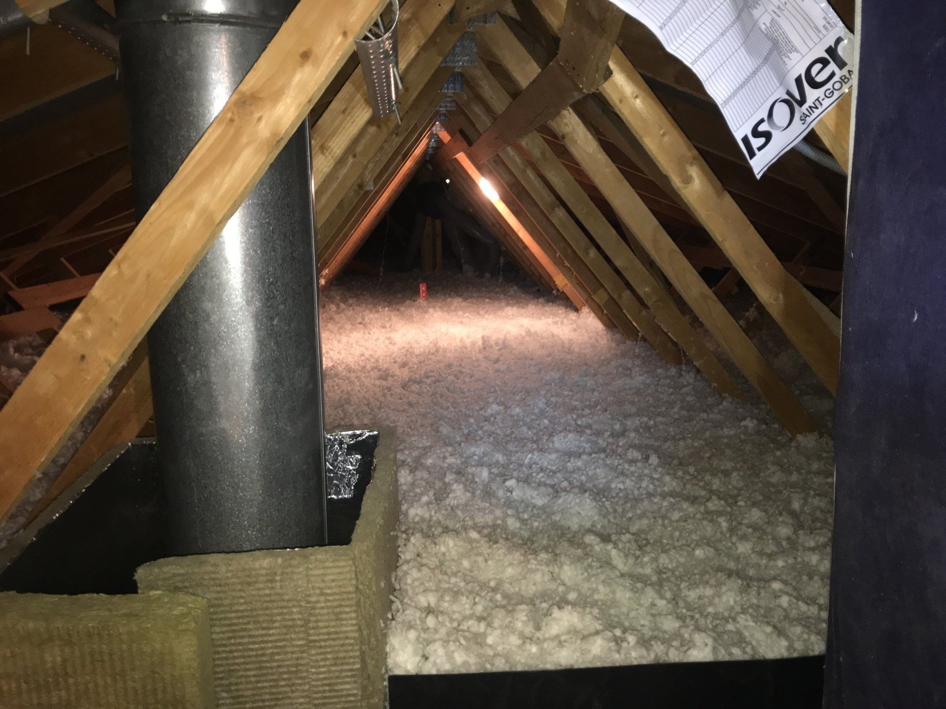 GTIsolation : Combles remplis de laine de verre blanche autour d'une cheminée 