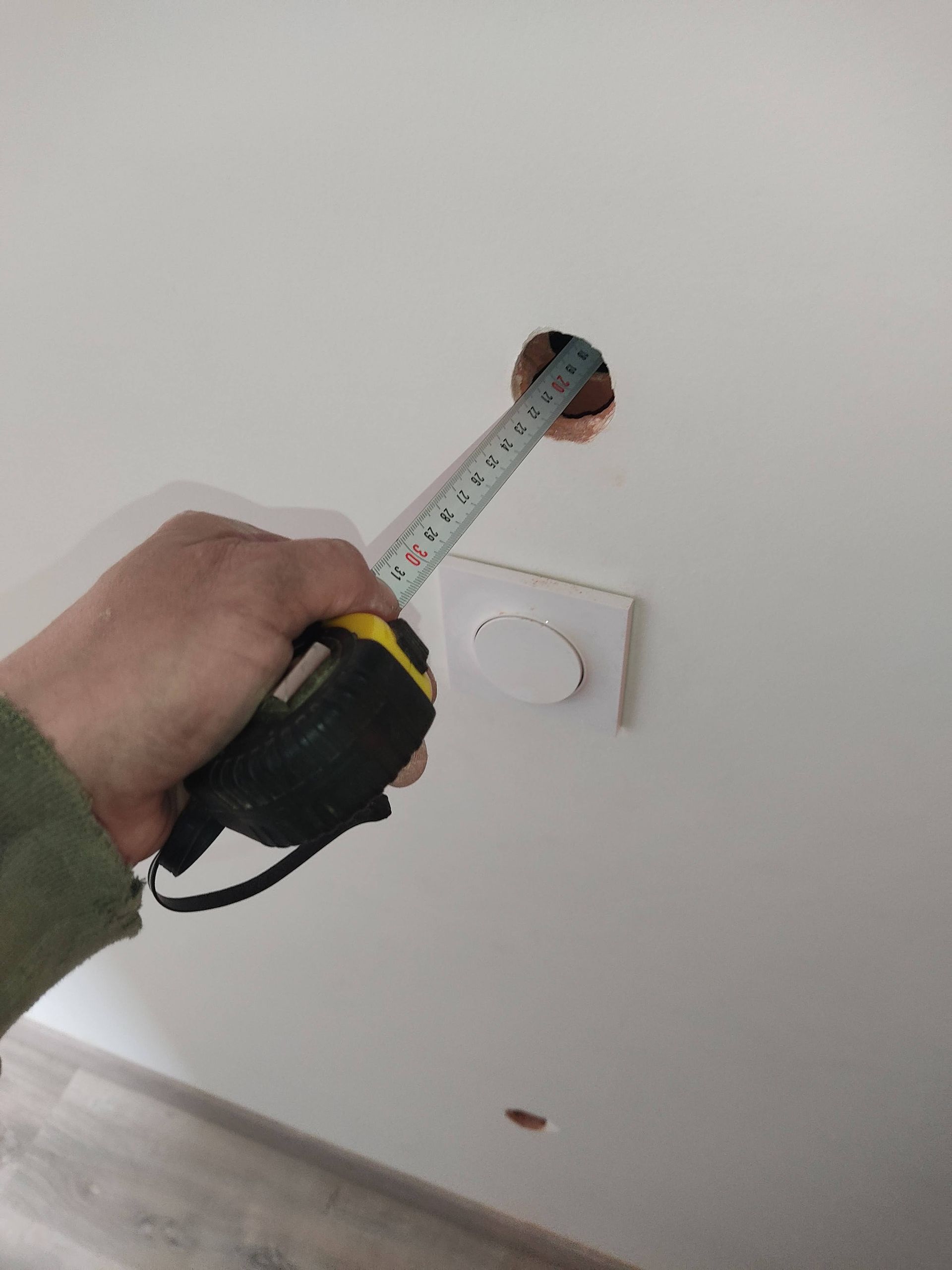 GTIsolation : Artisan insérant un mètre dans un mur pour mesurer la profondeur