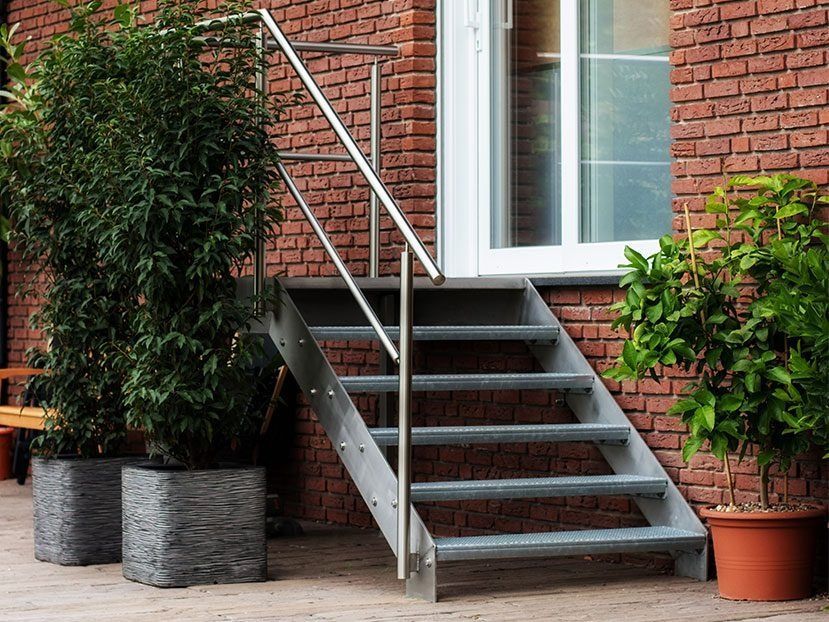 Metalltreppe neben einem Backsteingebäude mit Topfpflanzen am Fenster