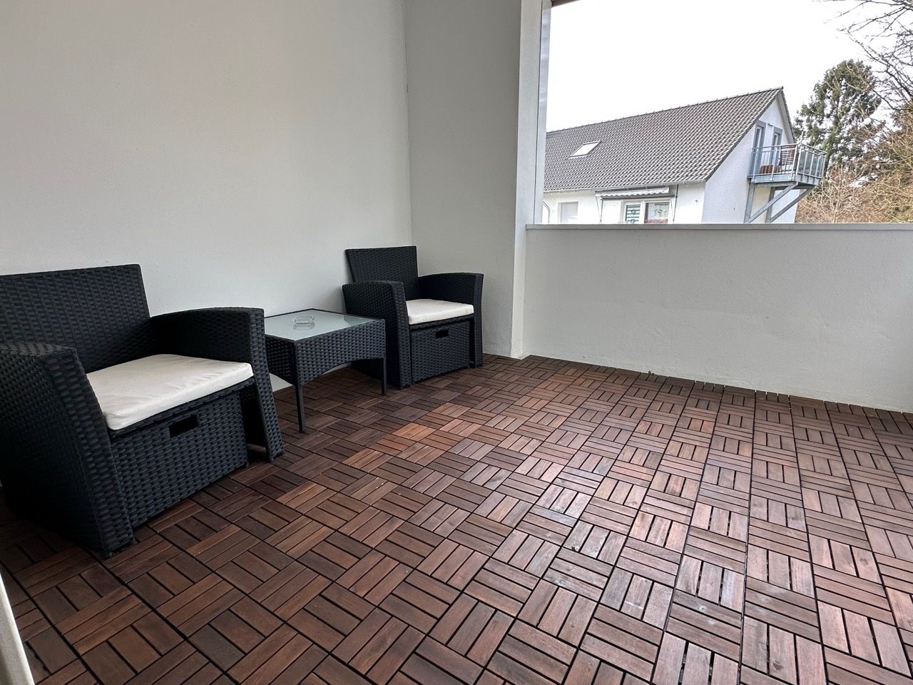 Ein Balkon mit zwei Stühlen und einem Tisch und einem Fenster.