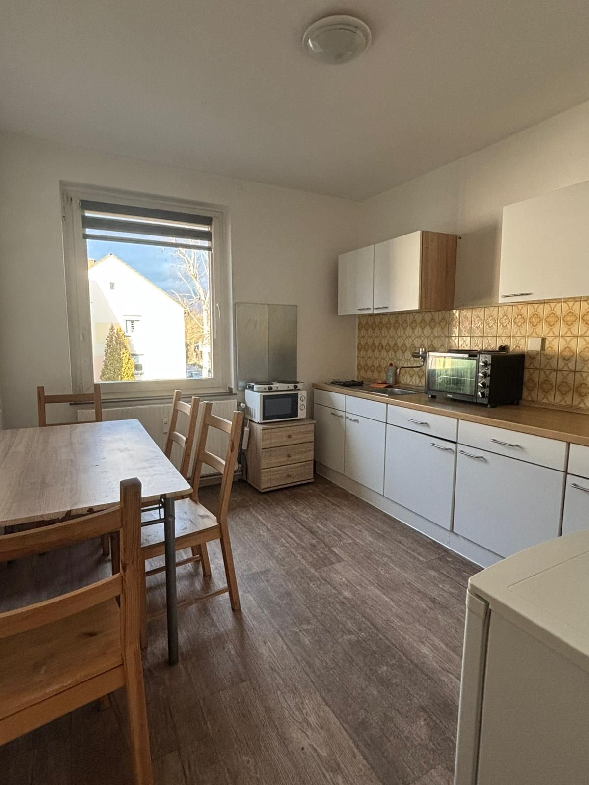 A kitchen with a table and chairs and a microwave.