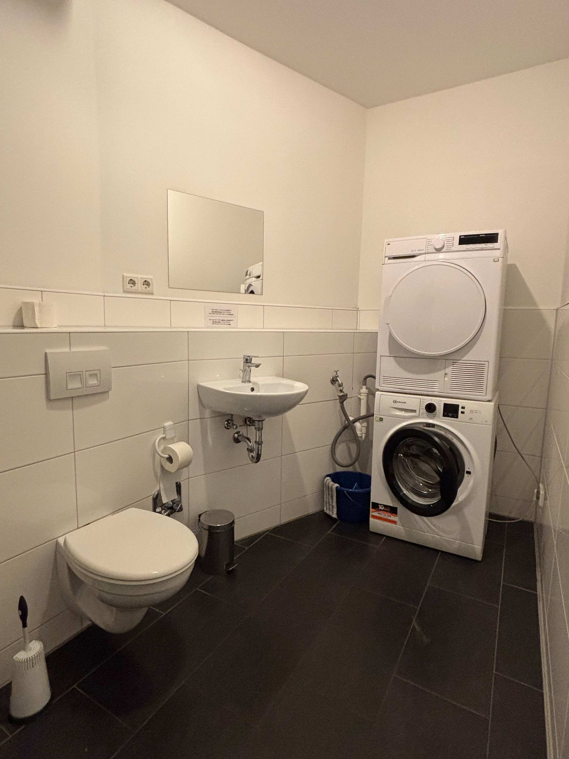 Ein Badezimmer mit Toilette, Waschbecken, Waschmaschine und Trockner.