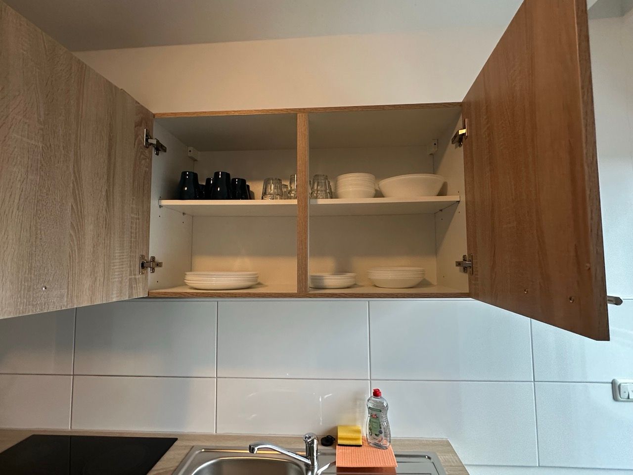 Eine Küche mit Spüle, Herd und Schränken mit offener Tür.