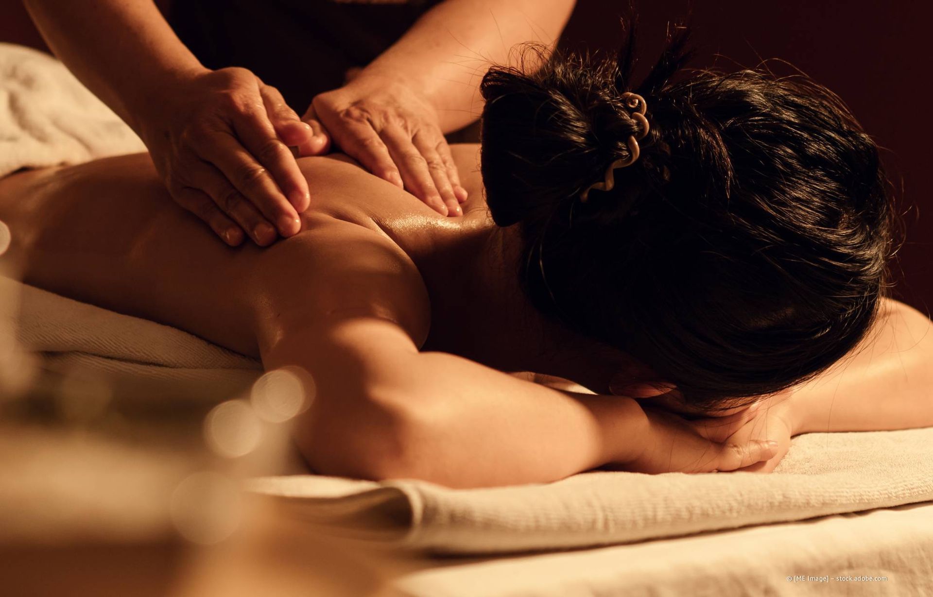 Frau erhält in einem Spa eine Rückenmassage; Hände kneten Muskeln.