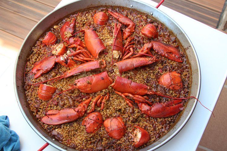 Una sartén llena de arroz y langostas sobre una mesa.