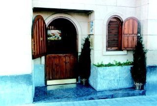 Un edificio con una puerta de madera y persianas en las ventanas
