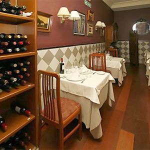 Un restaurante con mesas y sillas y botellas de vino en los estantes.