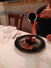 Una persona está vertiendo salsa de chocolate sobre un postre en un plato.