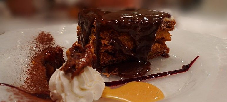 Un trozo de pastel de chocolate con crema batida en un plato blanco.
