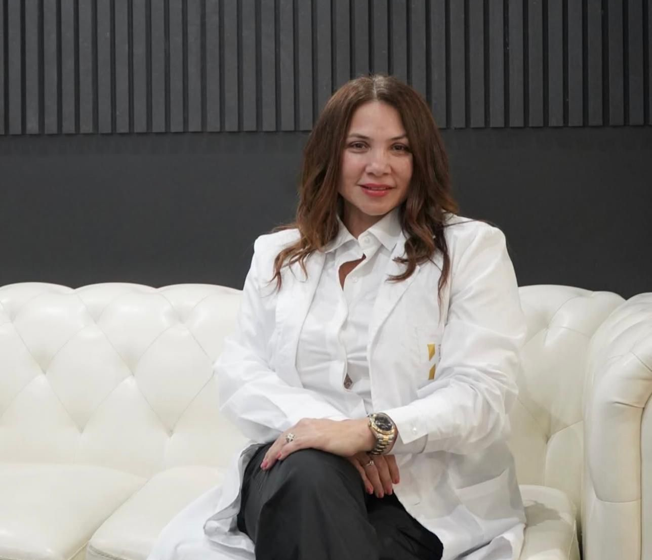 Una persona con bata blanca de laboratorio está sentada en un sofá