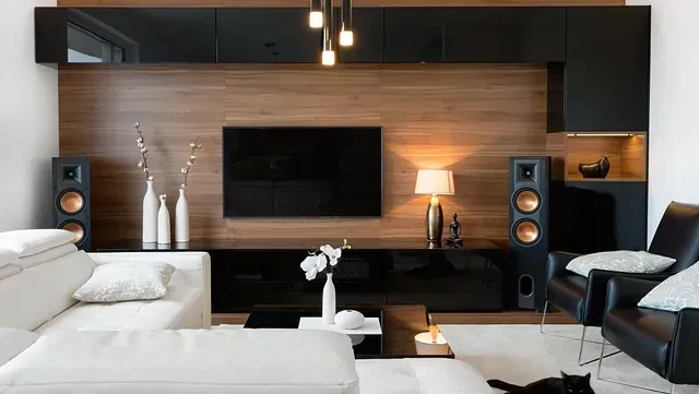 Una sala de estar con un sofá, una silla, parlantes y un televisor de pantalla plana.