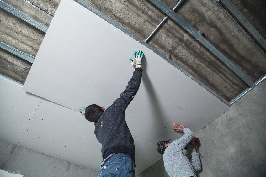 Dos hombres están trabajando en el techo de una habitación.