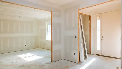 Una habitación vacía con paneles de yeso y una puerta en una casa en construcción.