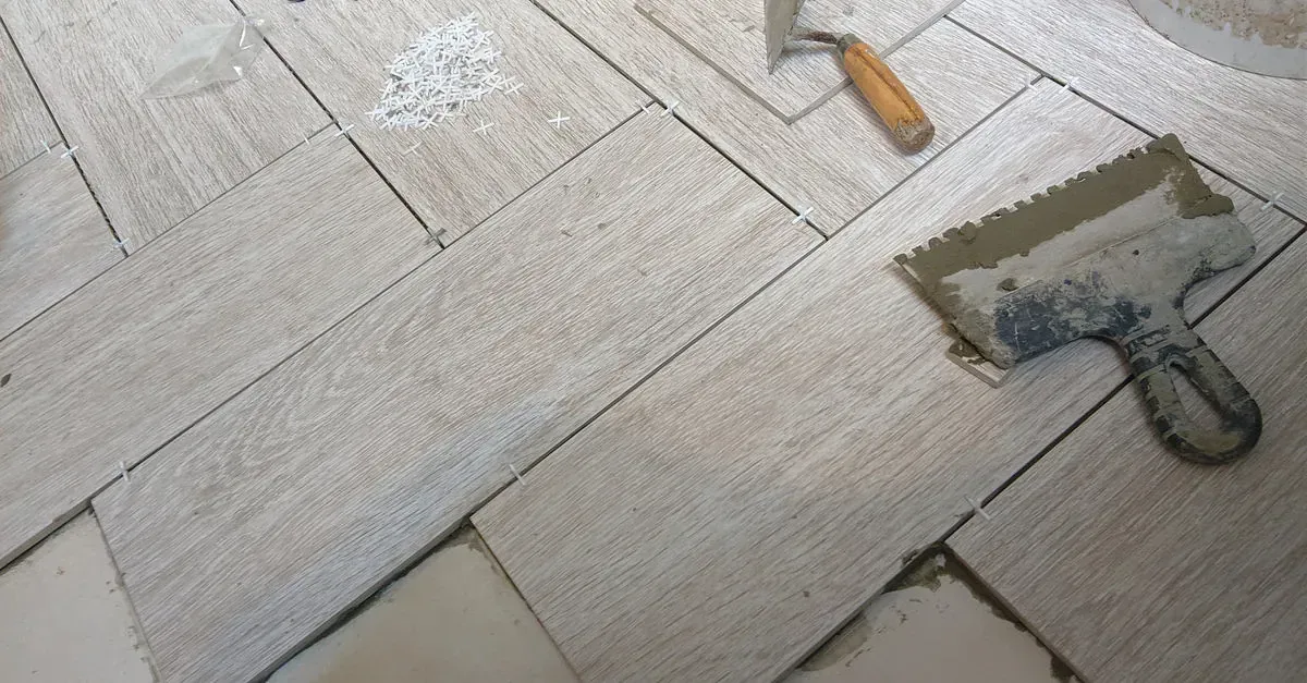 Una paleta está colocada sobre un suelo de baldosas al lado de un martillo.