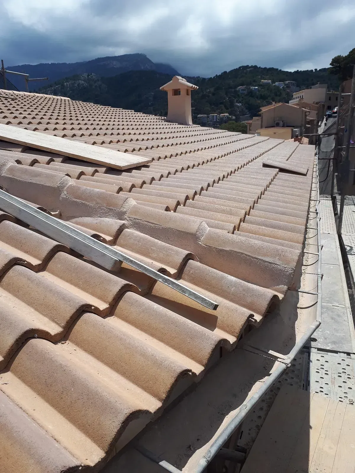 Un primer plano de un tejado de tejas con montañas al fondo.