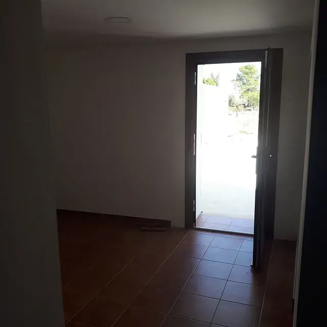 Una habitación vacía con una puerta abierta y una ventana.
