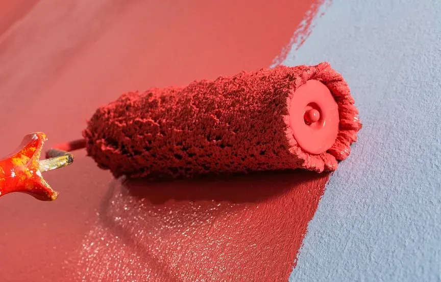 Se está utilizando un rodillo de pintura rojo para pintar una pared azul.