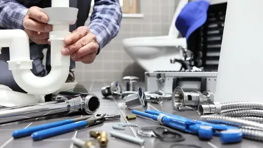 Un fontanero está arreglando una tubería en un baño.