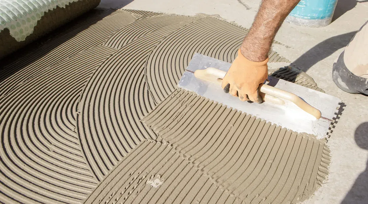 Una persona está extendiendo hormigón en el suelo con una paleta.