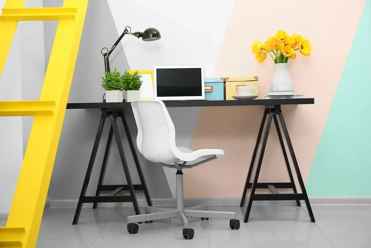 Una oficina en casa con escritorio, silla, lámpara y computadora portátil.