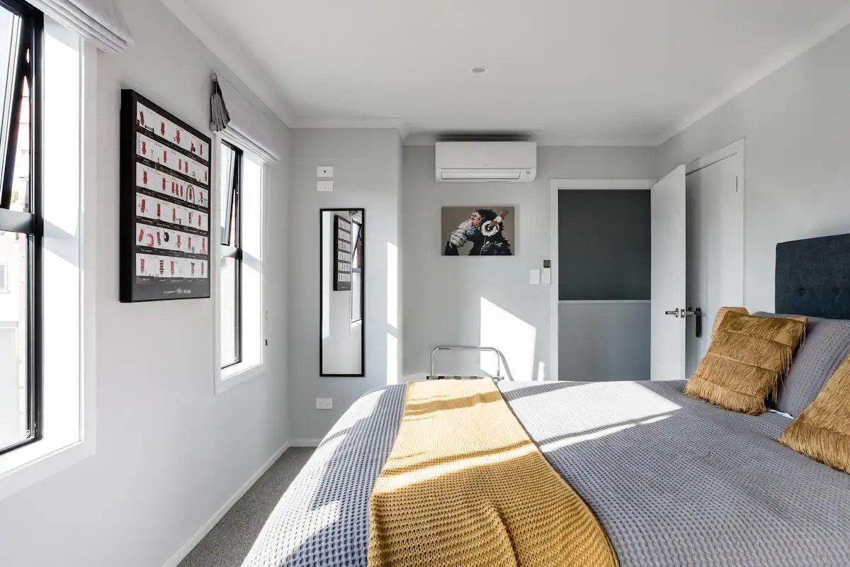 A bedroom with a bed , a mirror , and a window.