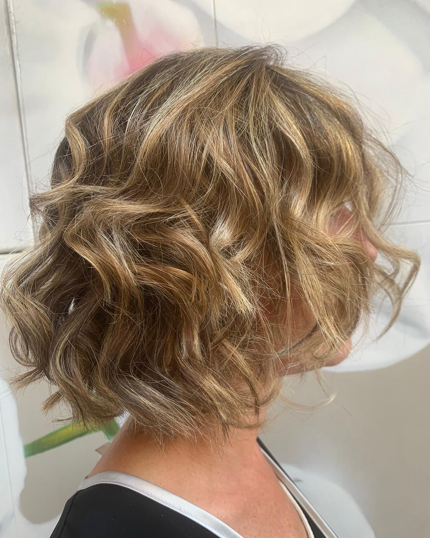 Una mujer con cabello corto y ondulado lleva una camisa negra.