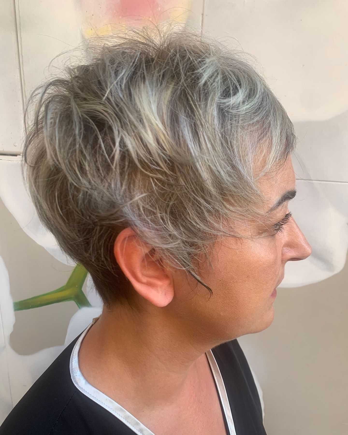 Una mujer con cabello corto y gris lleva una camisa negra.