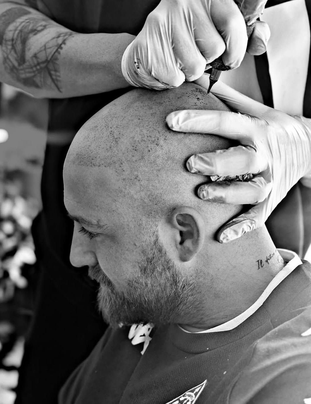 Un hombre calvo se hace un tatuaje en el cuero cabelludo.