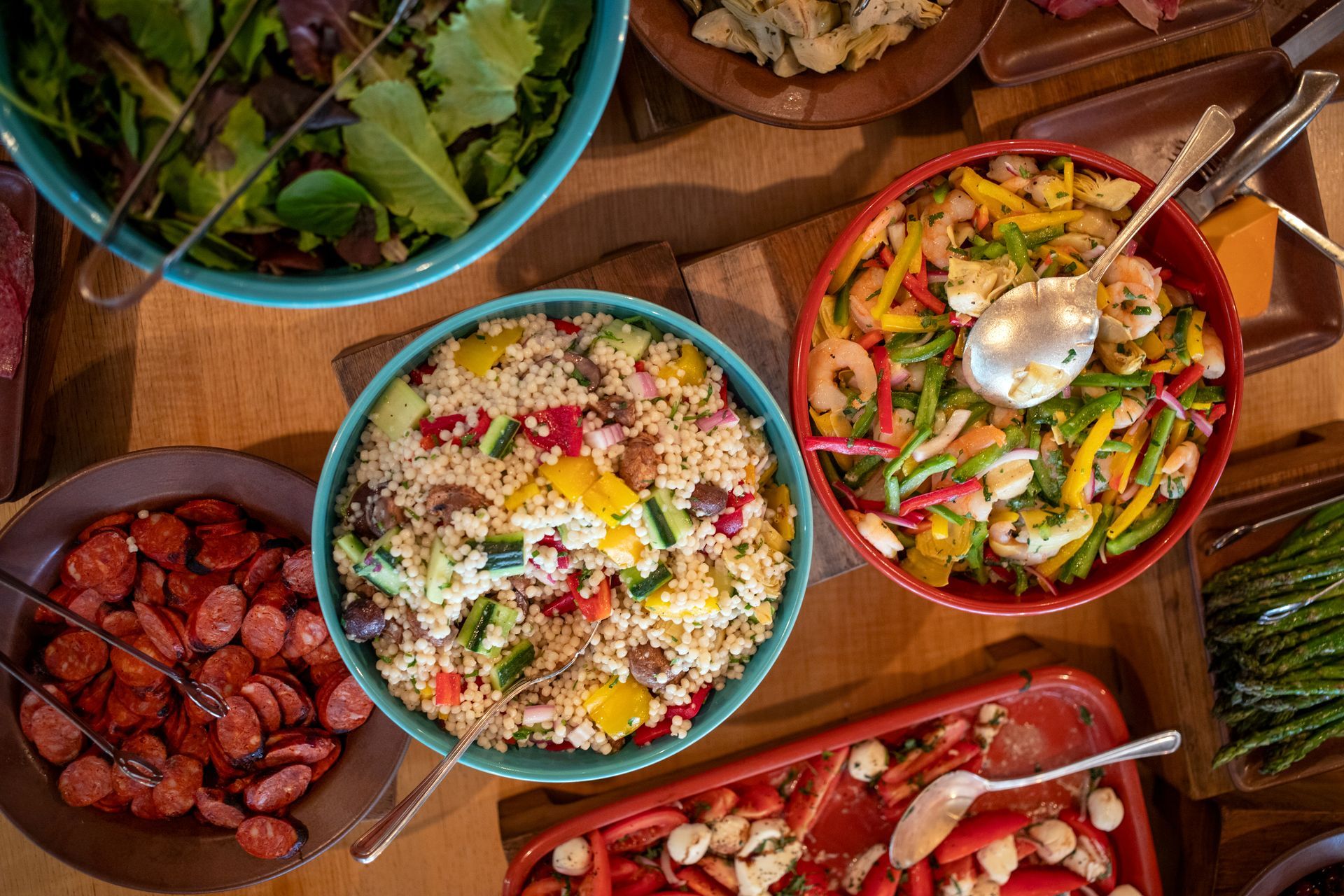 Bowls of couscous salad, shrimp, greens, and chorizo