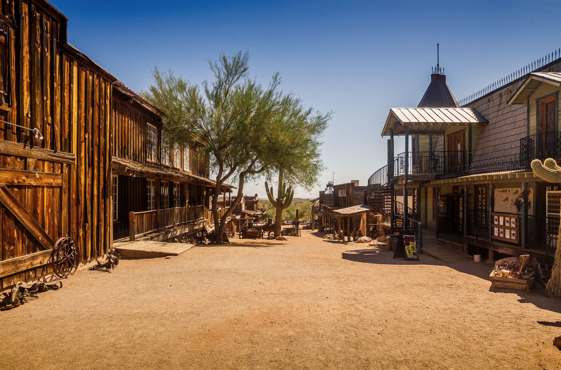 Old western-style street with wooden buildings, dusty road, and a clear blue sky