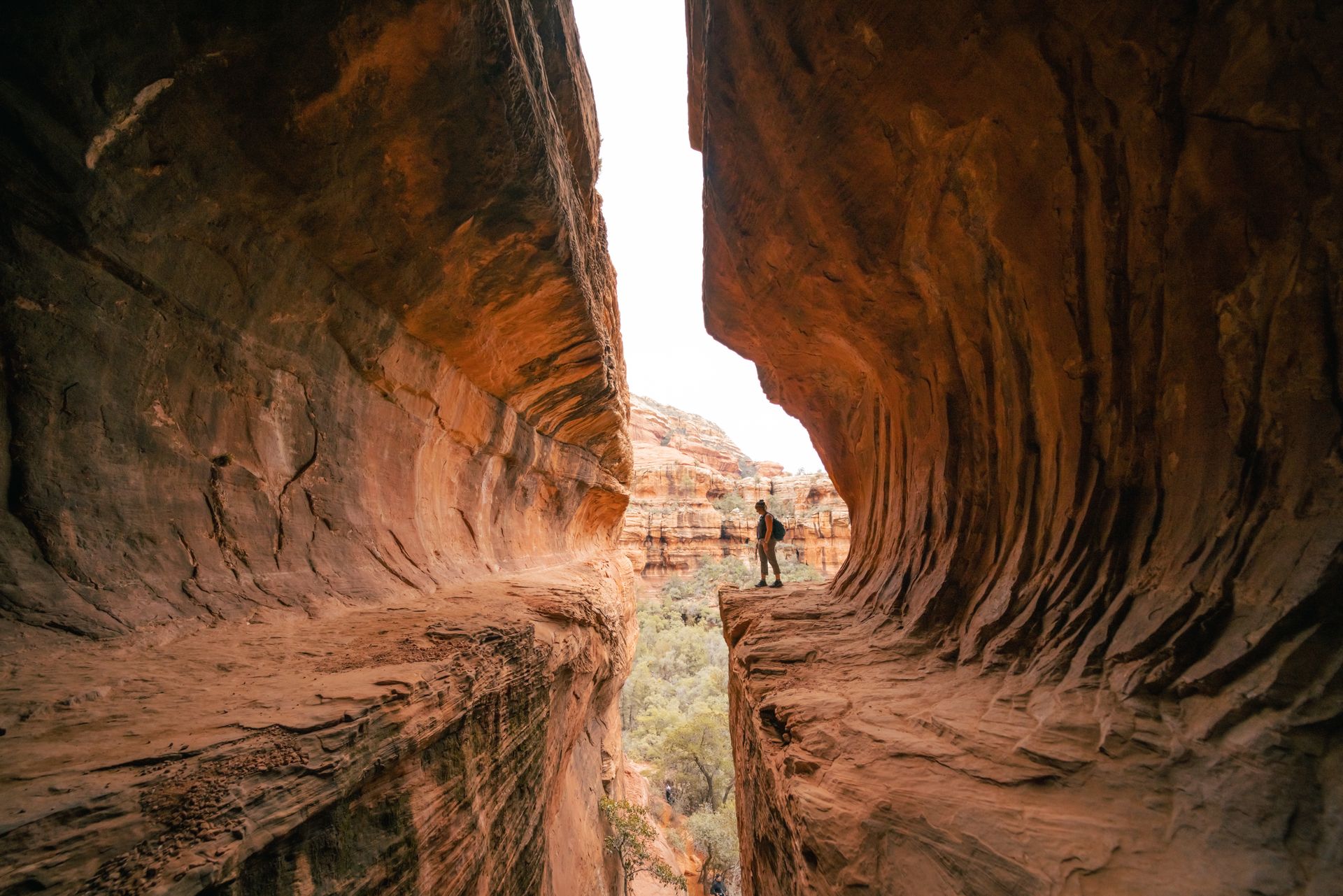 Narrow sandstone canyon with a person standing in the bright opening