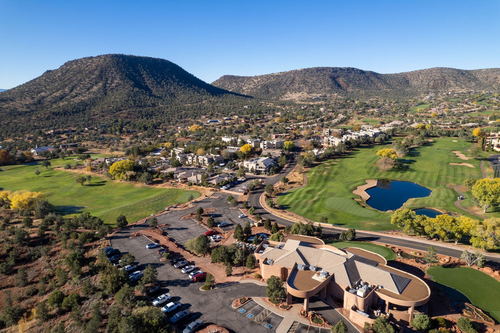 Aerial view of a golf course and resort town with mountains in the background