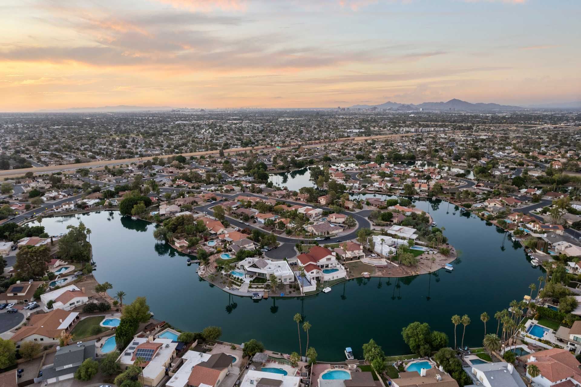 Aerial view of a suburban neighborhood surrounding a lake at sunset