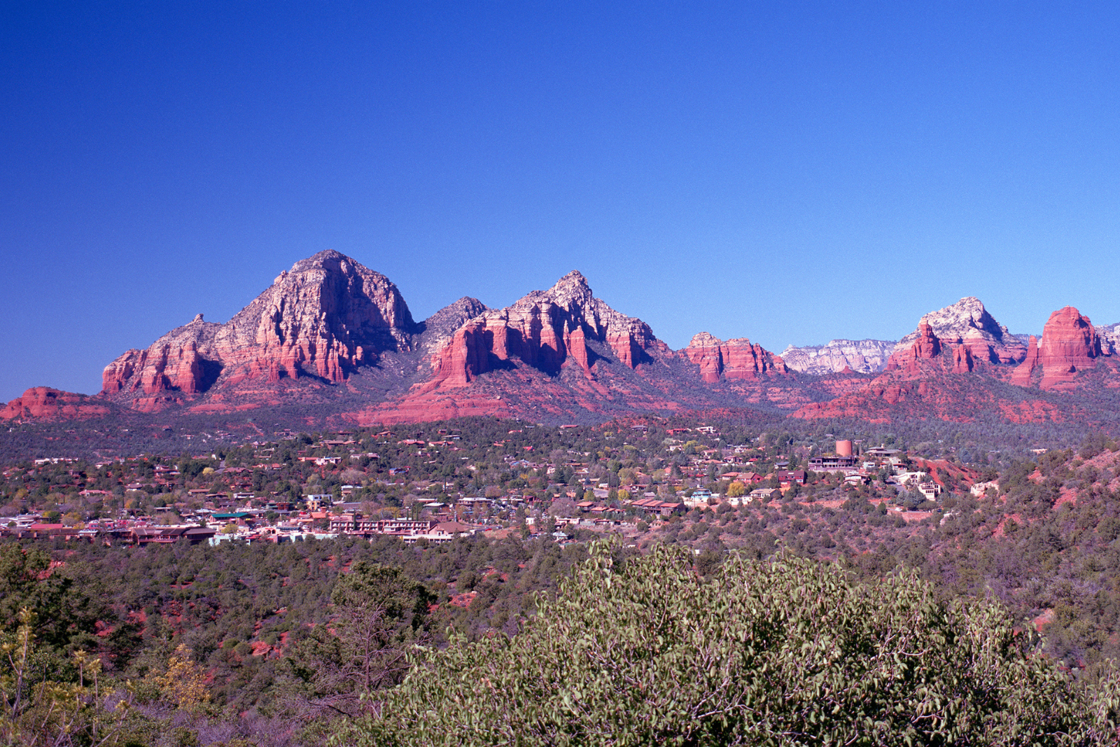 Red sandstone mountain range above a desert town under a clear blue sky